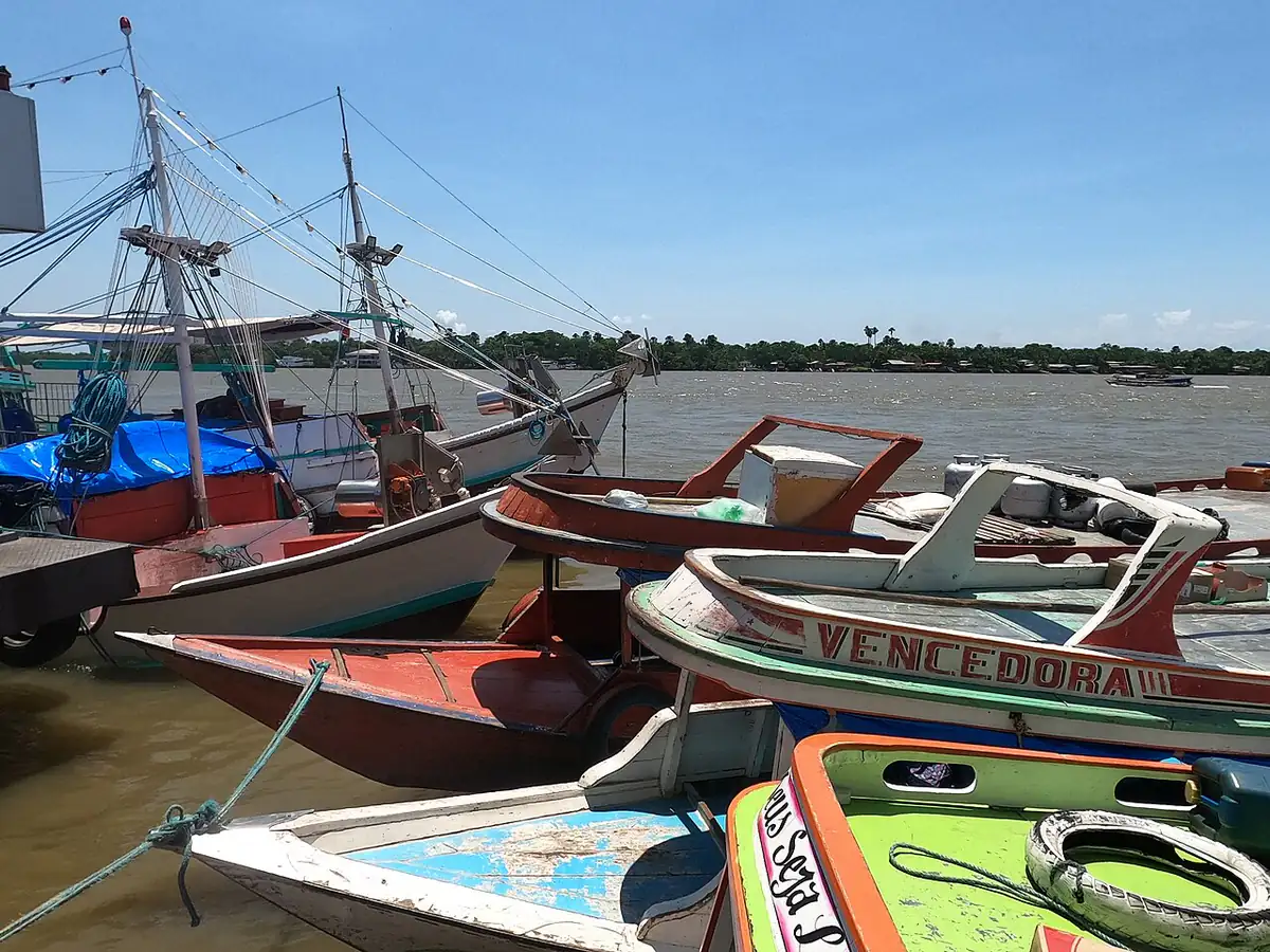 Barcos de madeira atracados na orla de Abaetetuba, com o rio e a outra margem ao fundo sob céu azul
