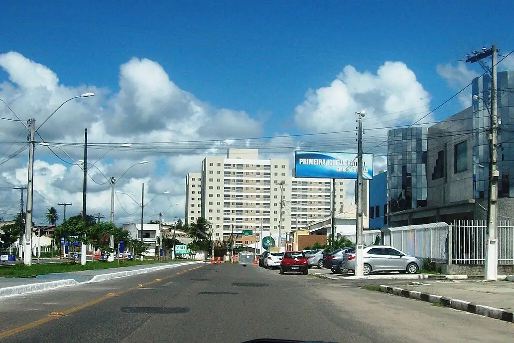 Rua de Alagoinhas com edifícios ao fundo sob céu azul com nuvens carregadas