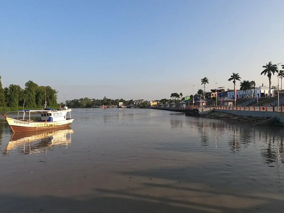 Barco de pesca no Rio Caeté, com a orla de Bragança à direita e céu limpo