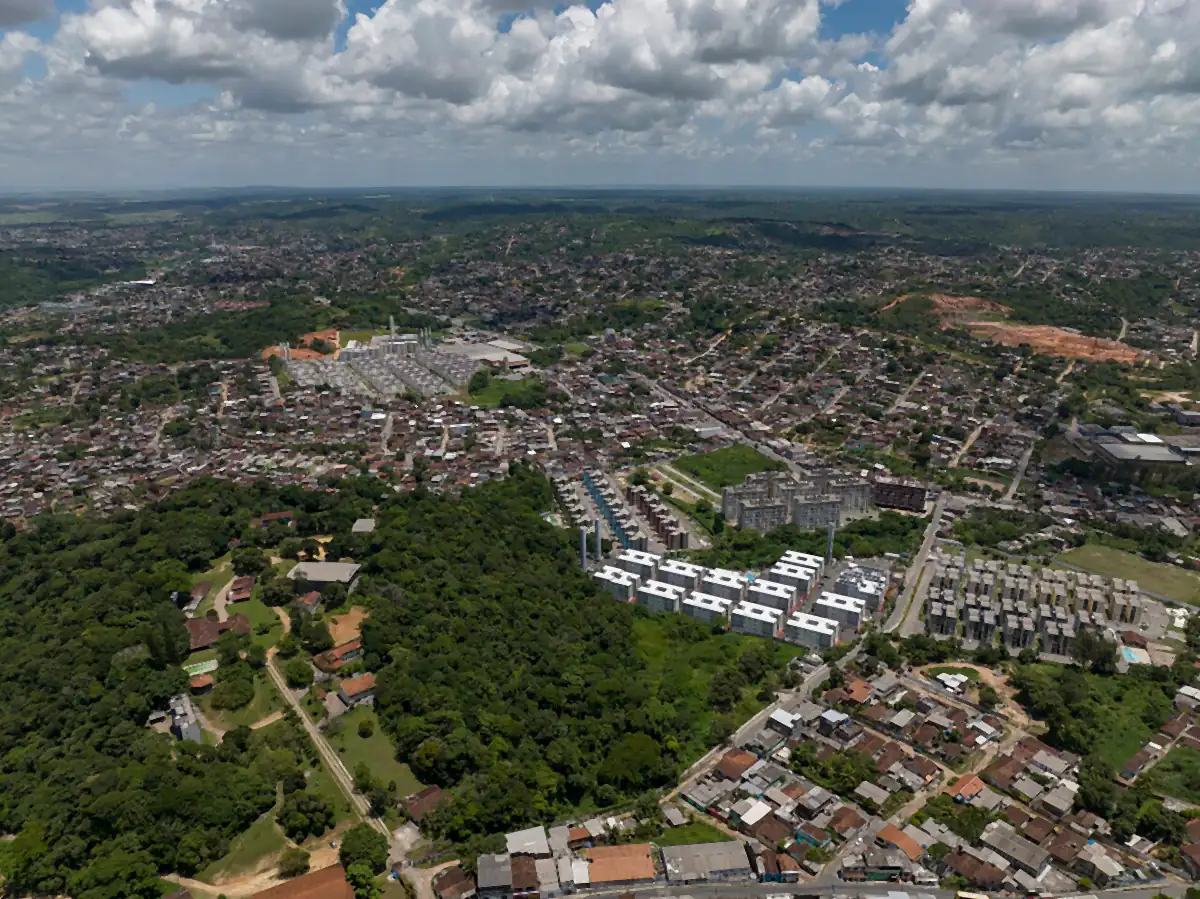 Vista aérea de Camaragibe, com mata, bairros e blocos de apartamentos sob céu com nuvens