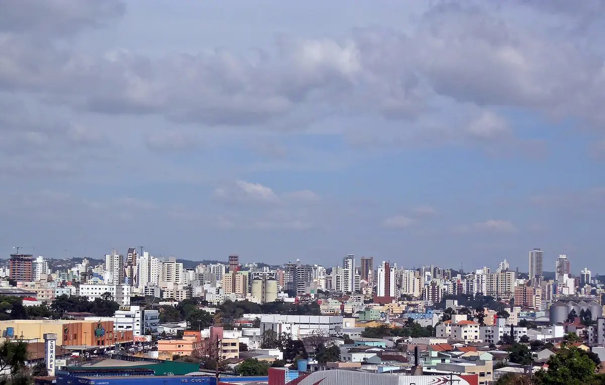 Prédios do centro de Chapecó sob um céu de nuvens carregadas, vistos de um ponto alto