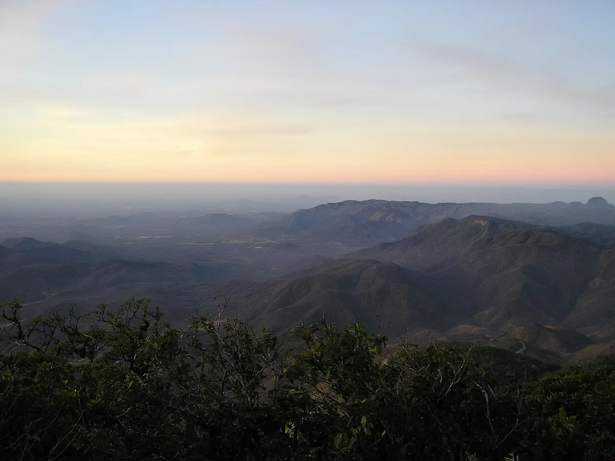 Serras do Maciço de Baturité vistas do Pico Alto ao entardecer, com névoa baixa e céu alaranjado