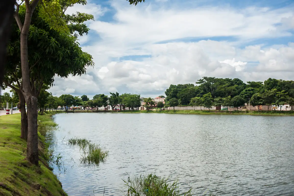 Céu com nuvens sobre um lago cercado de árvores, em Imperatriz