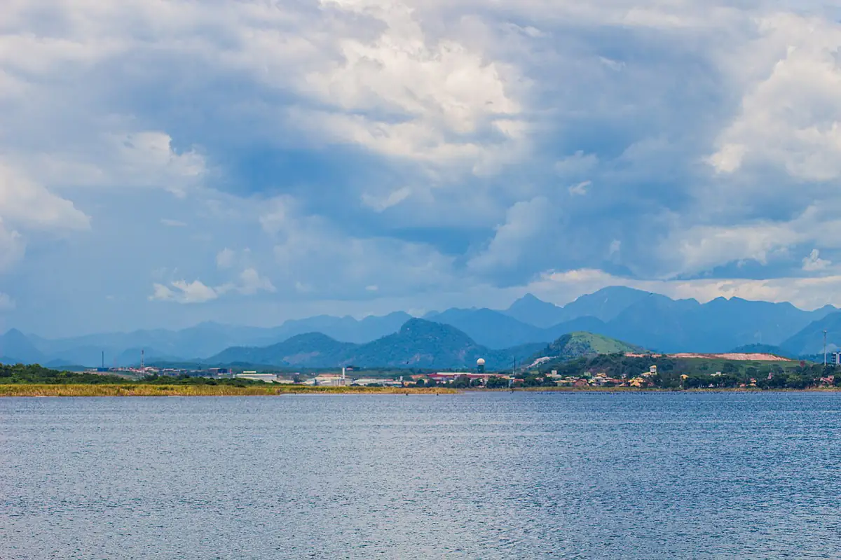 Céu carregado de nuvens sobre a Lagoa de Imboassica, em Macaé, com serras ao fundo