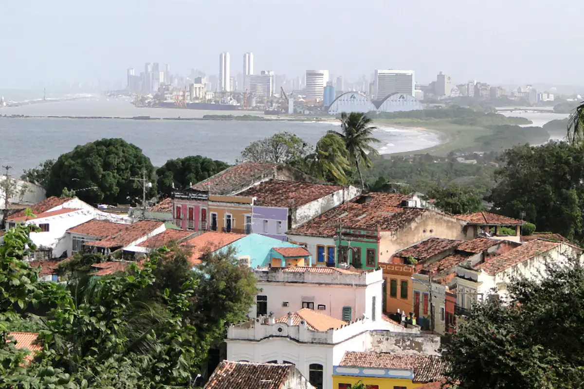 Telhados de Olinda vistos do Alto da Sé, com o mar e os prédios do Recife ao fundo sob céu enevoado