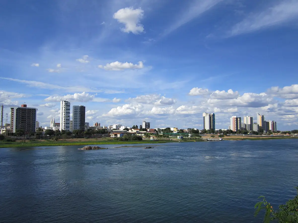 Rio São Francisco e prédios da orla de Petrolina sob céu azul com nuvens