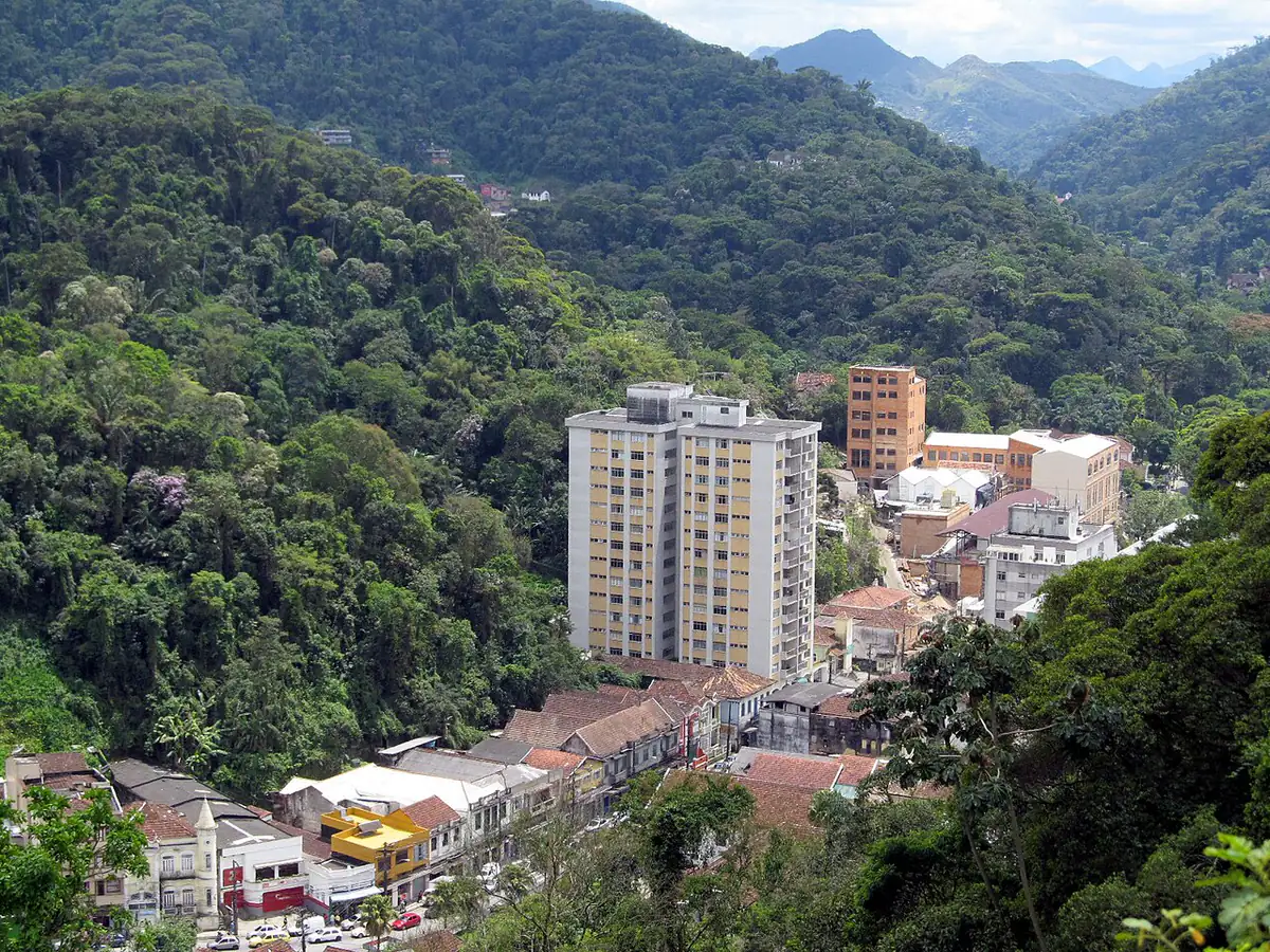 Prédios do centro de Petrópolis cercados por morros cobertos de mata, vistos de cima