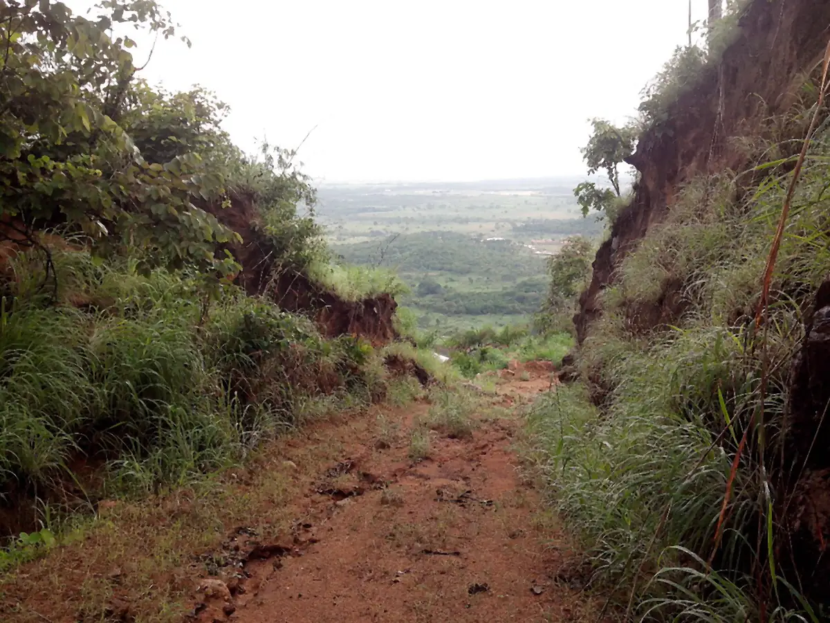 Trilha de terra entre barrancos com vista de mata e campos ao longe, nos arredores de Redenção
