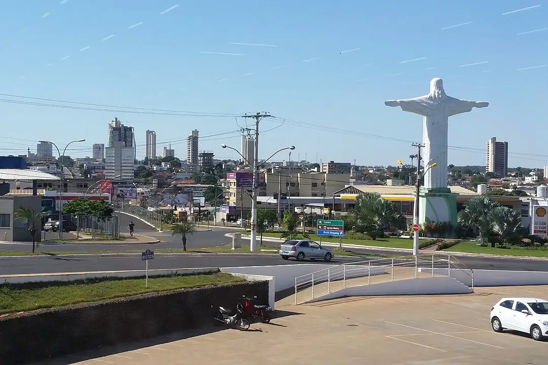 Vista de Rio Verde com prédios ao fundo, a estátua do Cristo em uma rotatória e céu azul