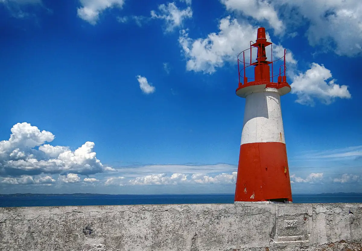 Farol de Monte Serrat, em Salvador, com céu azul e nuvens sobre a Baía de Todos os Santos