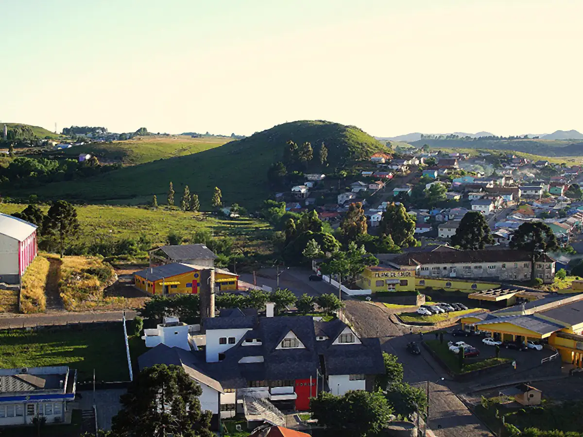 Vista do centro de São Joaquim com fórum, casas e colinas de campo ao fundo em luz baixa