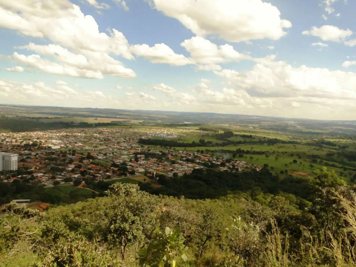 Senador Canedo vista do alto de um morro, com casas, pastos, cerrado e nuvens no céu