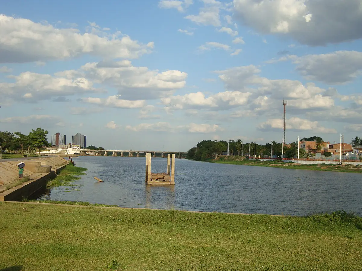 Rio Acaraú em Sobral, com a ponte ao fundo, prédios na margem e céu azul com nuvens