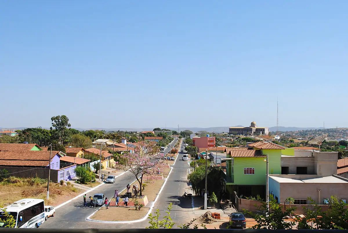 Rua de Trindade vista do alto, com casas de telhado colonial, a basílica ao fundo e céu azul sem nuvens