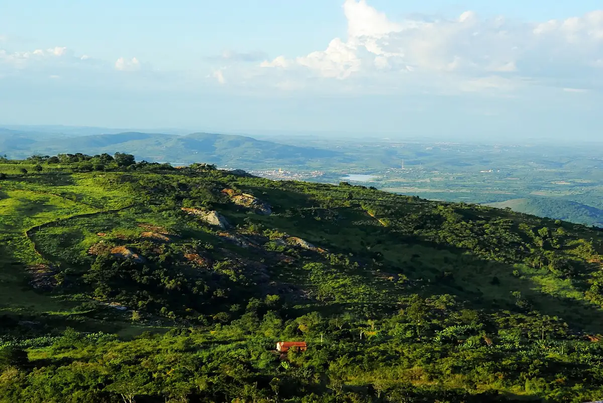 Encosta verde da serra em Triunfo, com a planície do sertão ao fundo sob céu com nuvens